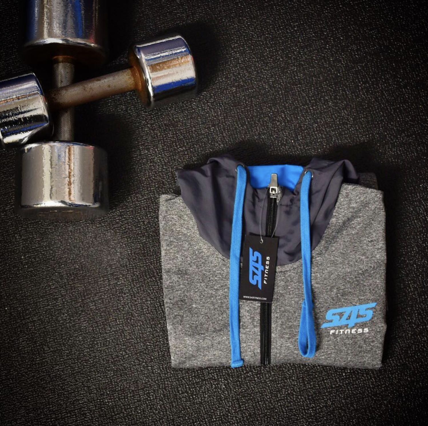 Hoodie folded beside dumbbells, showing the blue hood lining and swing tag