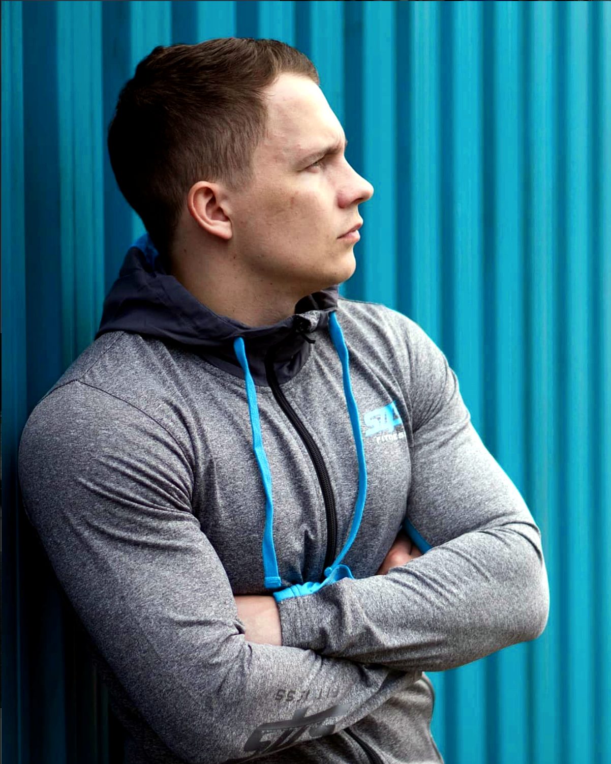 Side profile in the hoodie against a blue wall